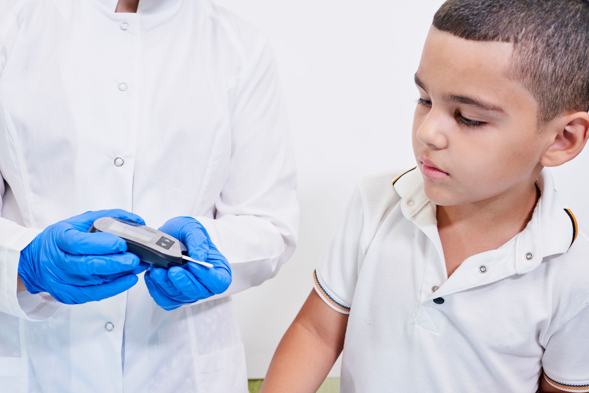 A nurse testing young boy for diabetes