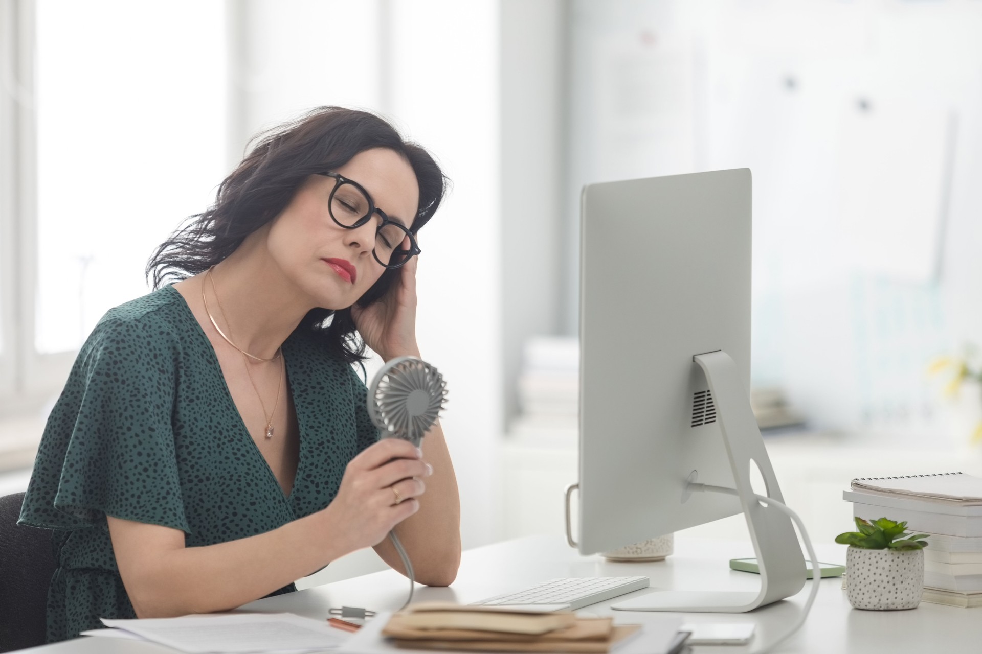 Mature woman suffering hot flash in the office