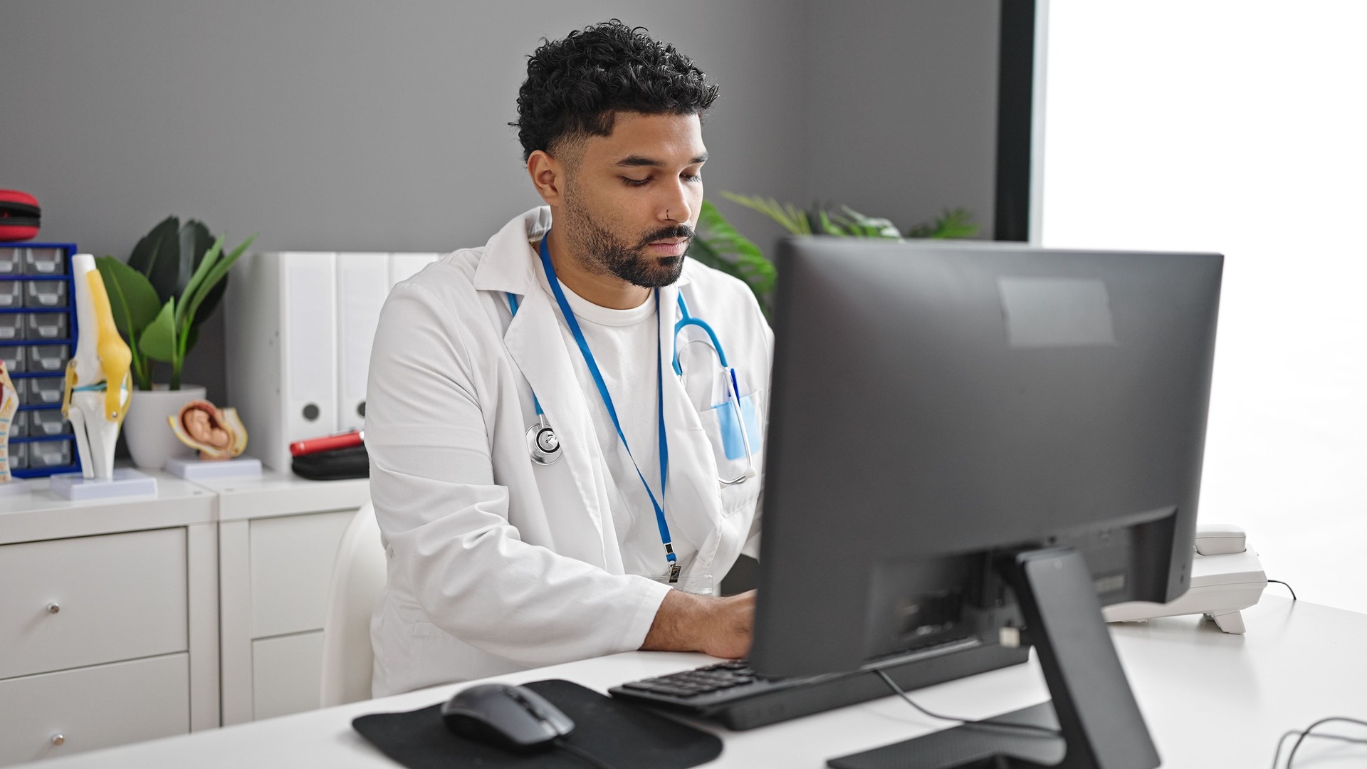 African american man doctor using computer working at clinic