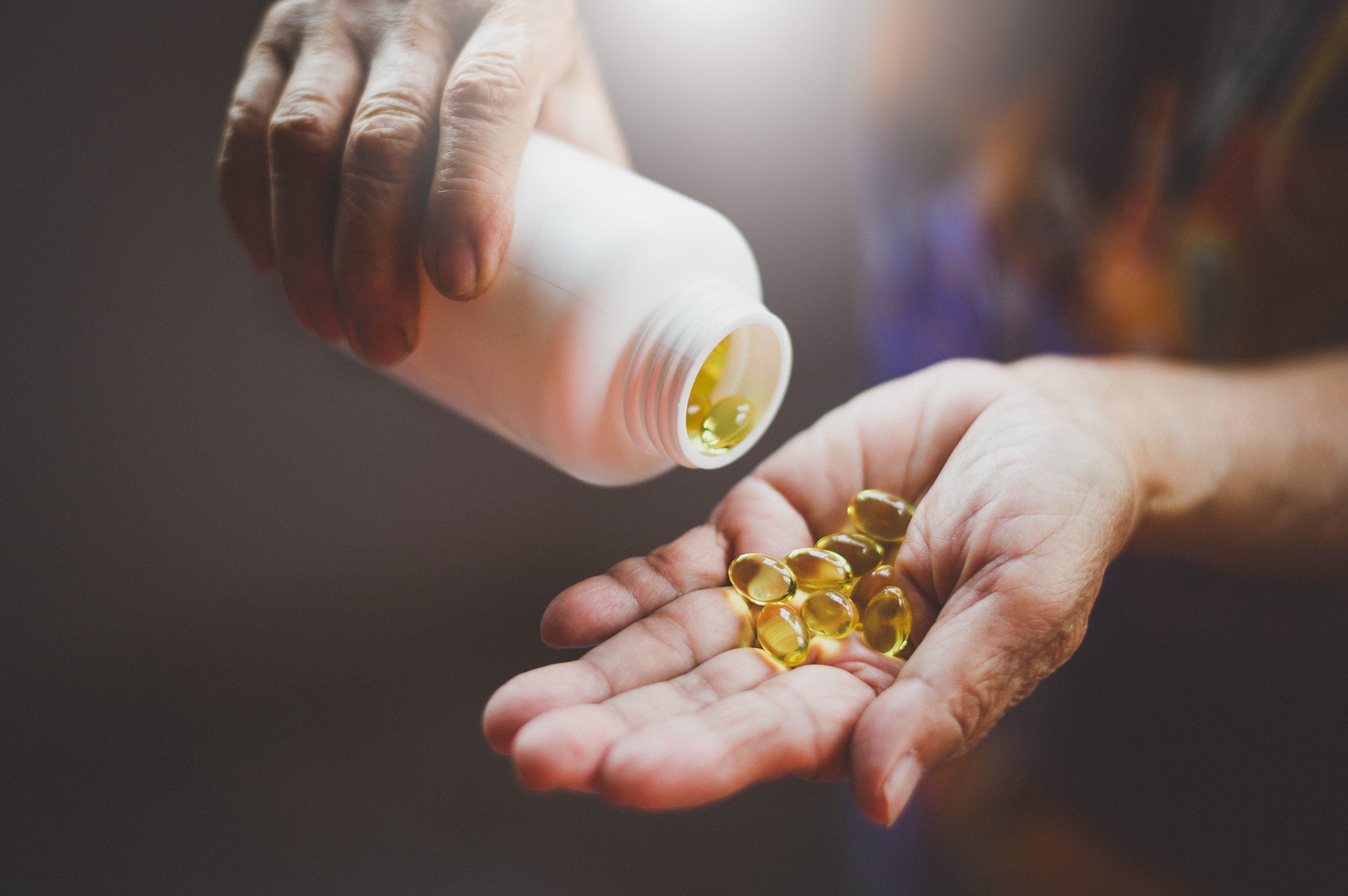 Bottle of omega 3 fish oil capsules pouring into hand