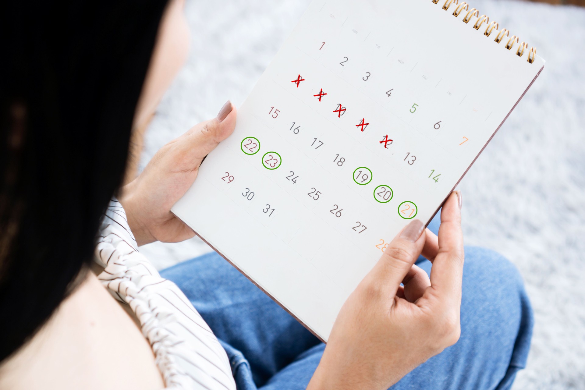 woman hand holding calendar counting the date and checking her menstrual cycle planning for ovulation